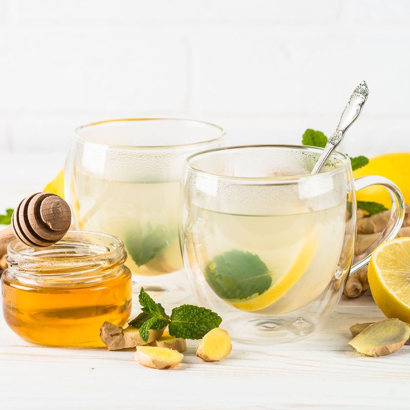 Zwei Gläser Ingwer-Zitronen-Tee mit Honig und frischer Minze
