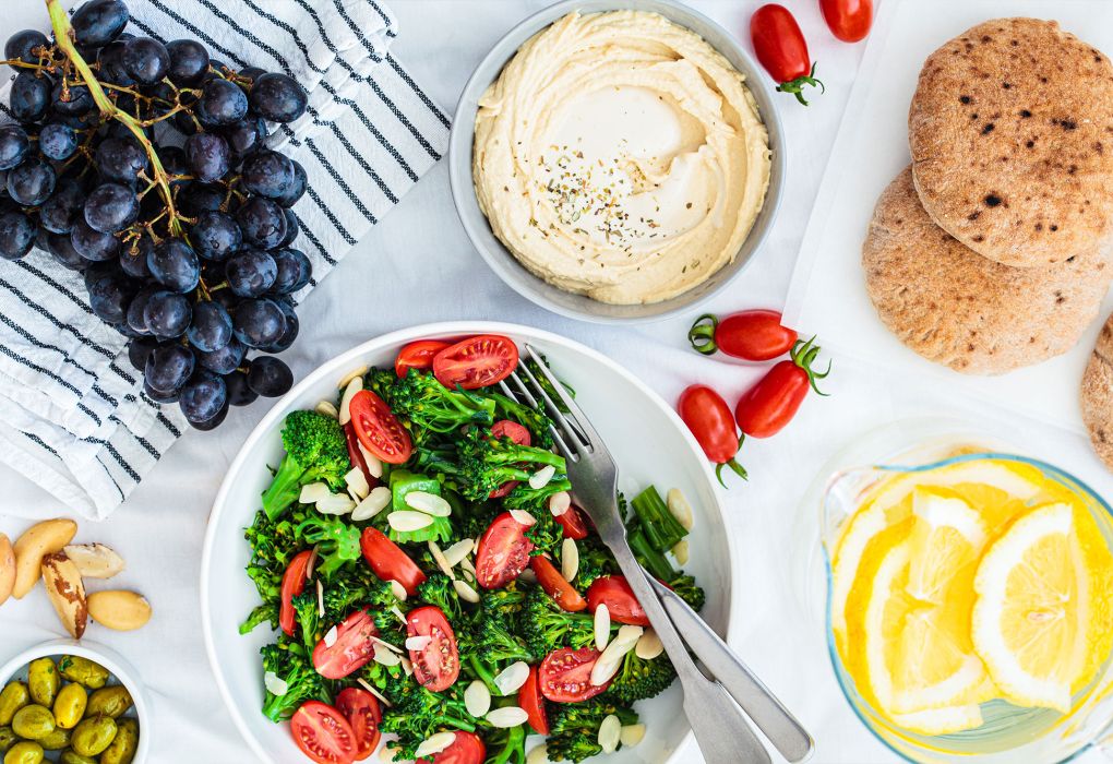 Oliven, Gemüse, Brot und Dip in Schalen, von oben fotografiert.