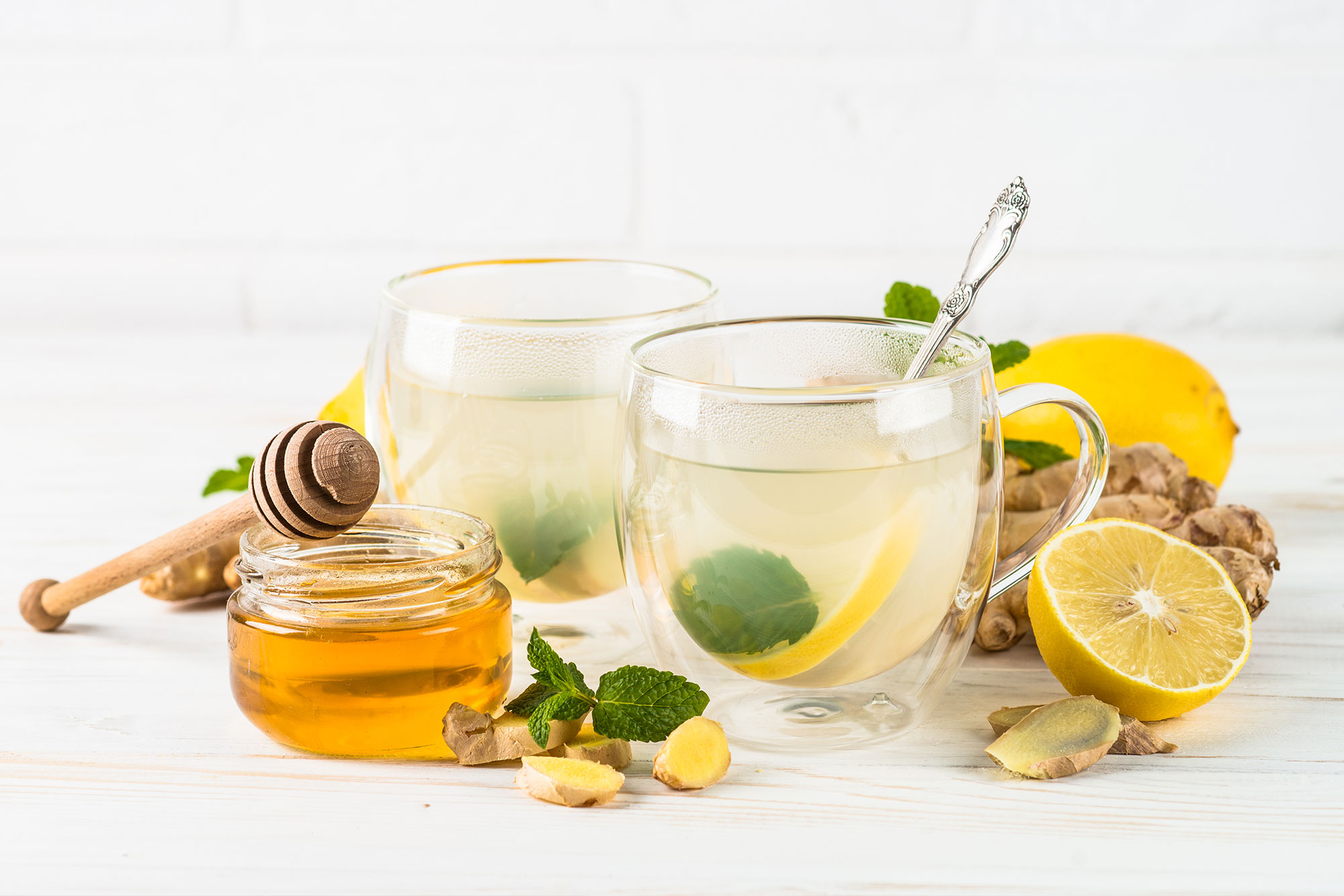 Zwei Gläser Ingwer-Zitronen-Tee mit Honig und frischer Minze